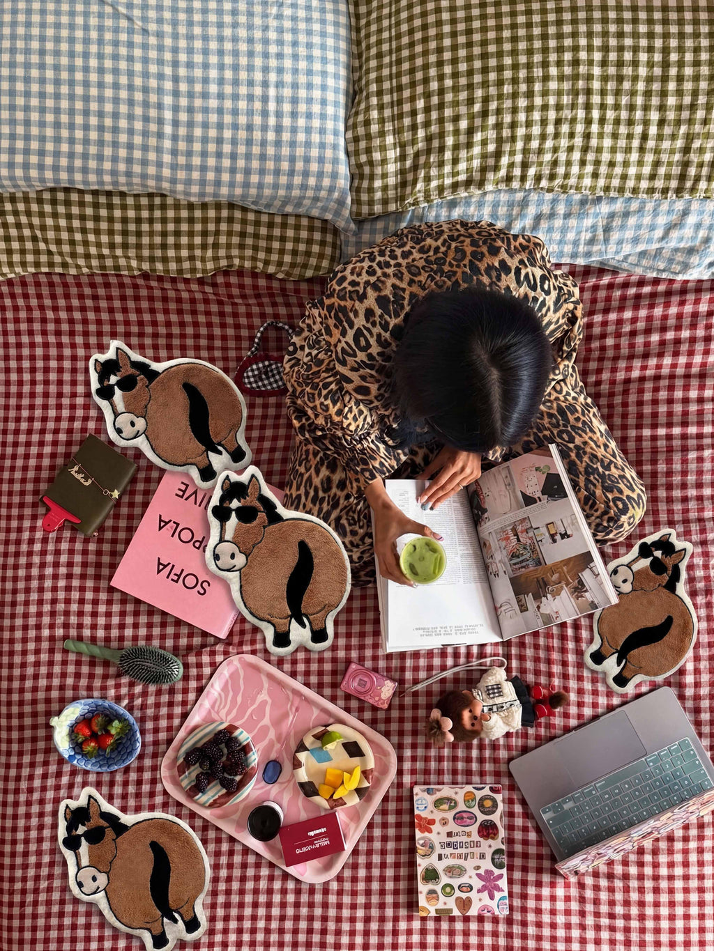 Flat-lay scene with Year of the Horse Flattery hand towels surrounded by magazines, snacks, stickers, and laptop on checkered blanket