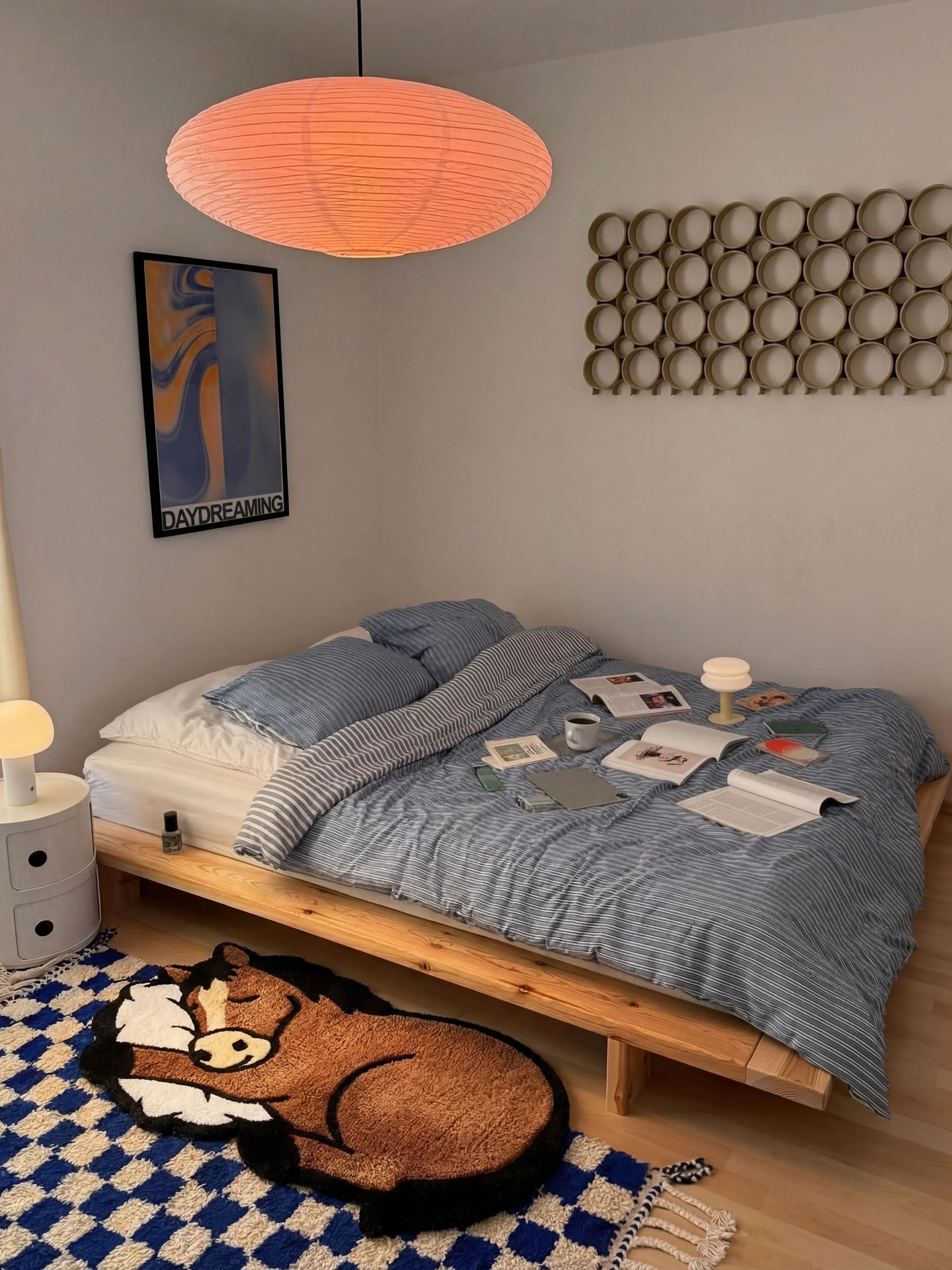 Sleep Right Neigh horse rug layered on checkered runner at foot of low bed in Japandi bedroom with paper pendant lamp